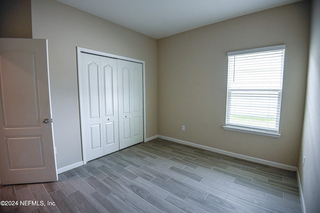 unfurnished bedroom featuring multiple windows, a closet, and hardwood / wood-style flooring