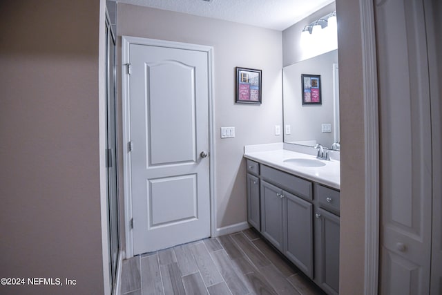 bathroom with a textured ceiling, vanity, and hardwood / wood-style floors