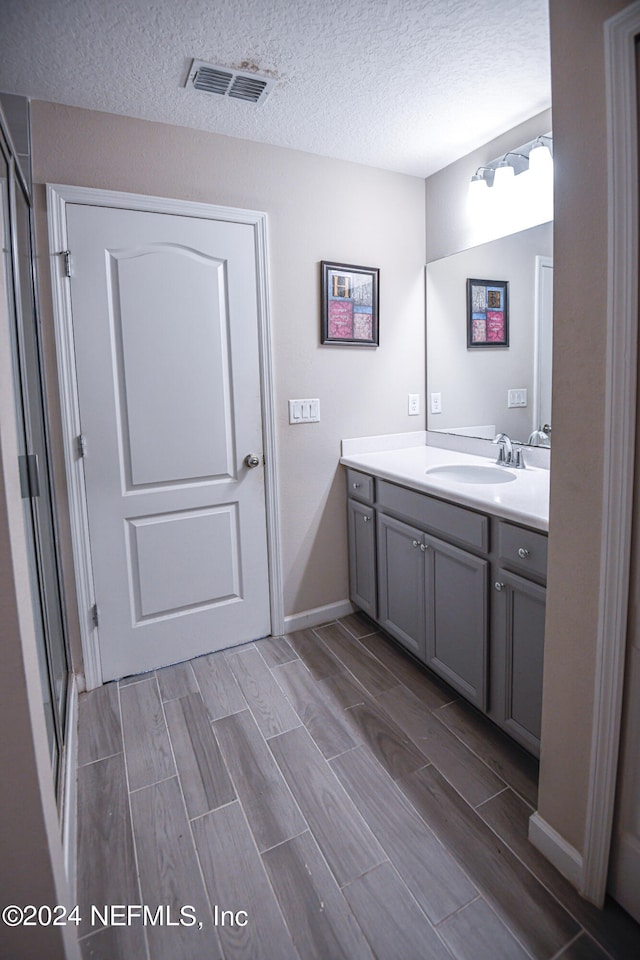 bathroom featuring vanity, a textured ceiling, and an enclosed shower