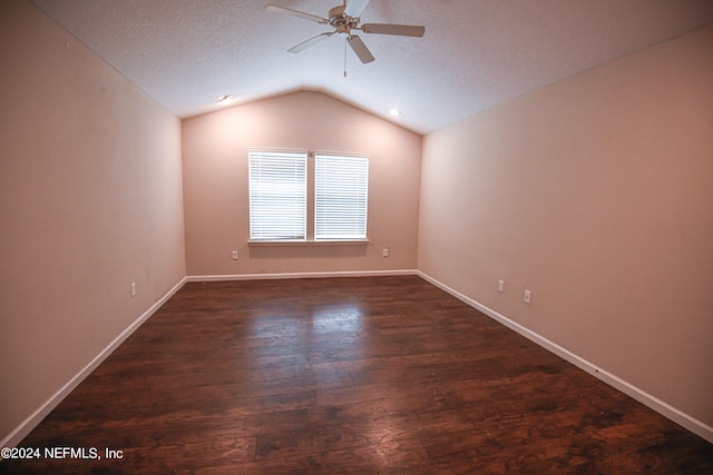 empty room with ceiling fan, a textured ceiling, lofted ceiling, and dark hardwood / wood-style flooring