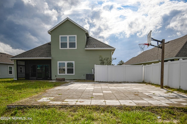 back of property with a lawn, a sunroom, and a patio area