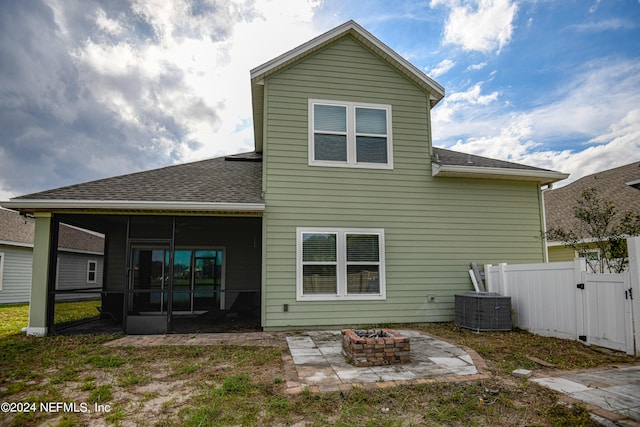 rear view of property featuring a sunroom, a patio area, and a fire pit