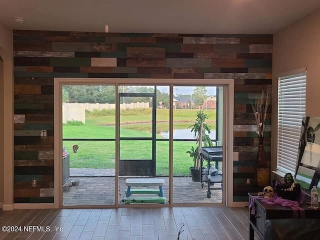 entryway with hardwood / wood-style flooring, wooden walls, and plenty of natural light