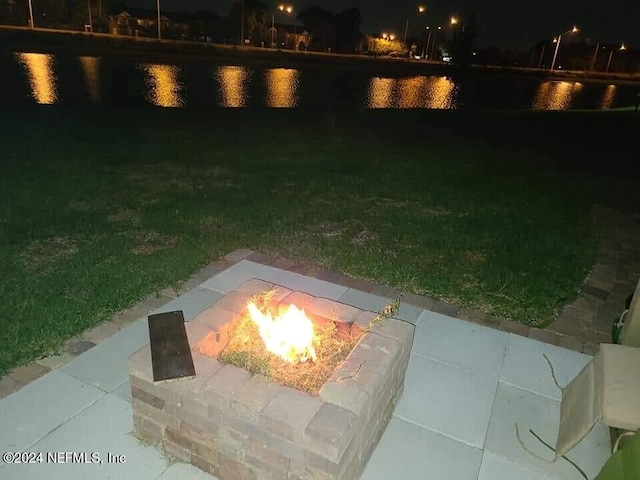 yard at twilight with a water view and an outdoor fire pit