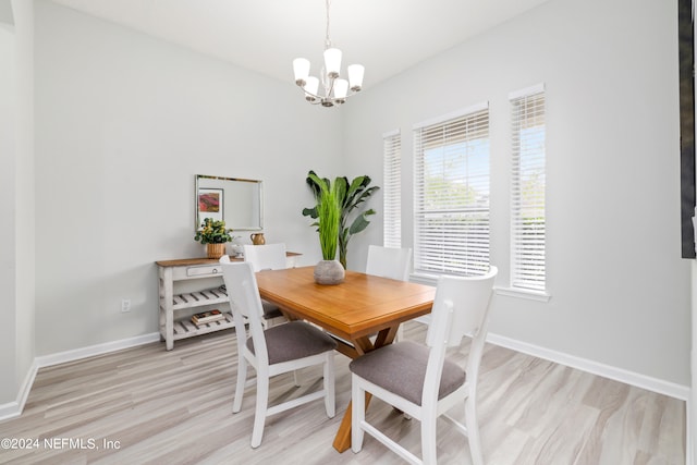 dining space with light hardwood / wood-style floors and a chandelier