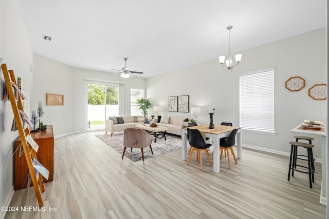 dining area with ceiling fan with notable chandelier and light hardwood / wood-style flooring