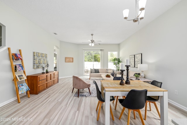 dining room with ceiling fan with notable chandelier and light hardwood / wood-style flooring