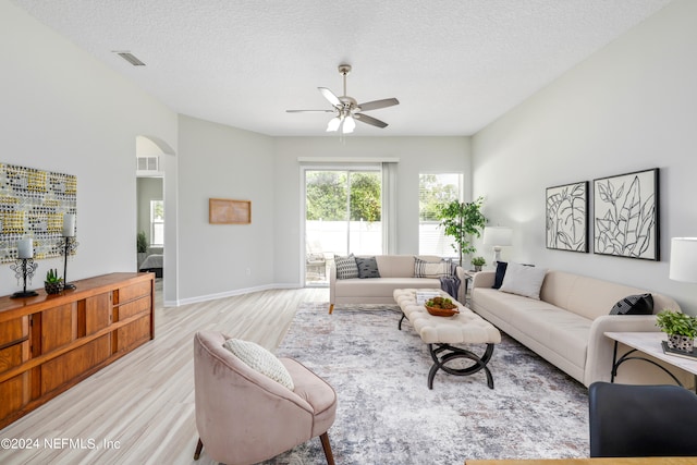 living room featuring ceiling fan, a textured ceiling, and light hardwood / wood-style flooring