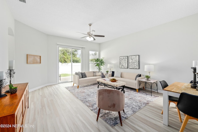 living room with a textured ceiling, light hardwood / wood-style floors, and ceiling fan