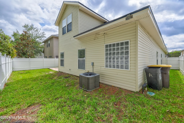 back of property with cooling unit and a yard