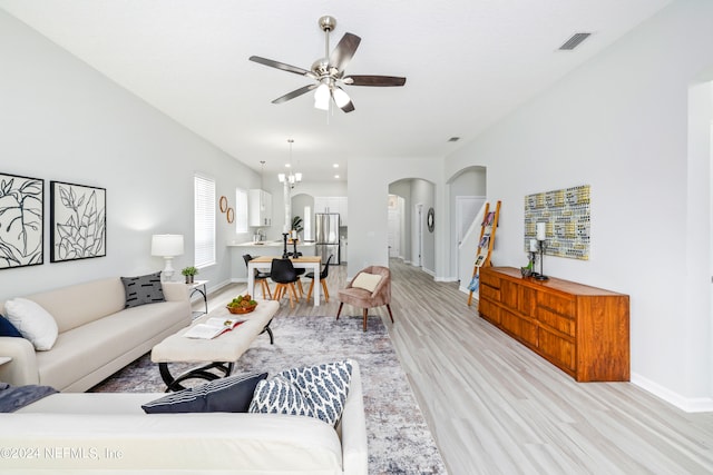 living room featuring ceiling fan with notable chandelier and light hardwood / wood-style floors