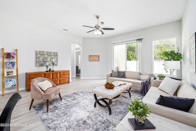 living room with light wood-type flooring, ceiling fan, and a textured ceiling