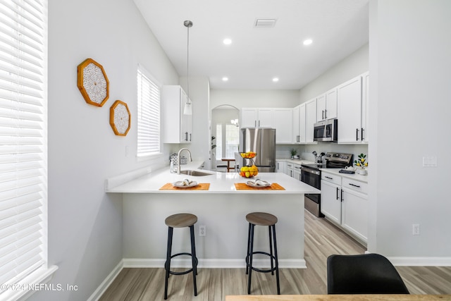 kitchen featuring white cabinets, stainless steel appliances, kitchen peninsula, and a kitchen breakfast bar