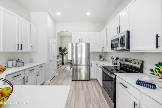 kitchen with light wood-type flooring, white cabinetry, and appliances with stainless steel finishes