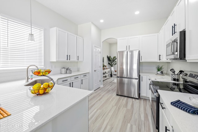 kitchen with appliances with stainless steel finishes, white cabinets, sink, and decorative light fixtures