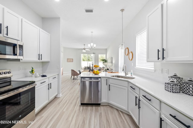 kitchen with appliances with stainless steel finishes, hanging light fixtures, light hardwood / wood-style floors, white cabinets, and sink