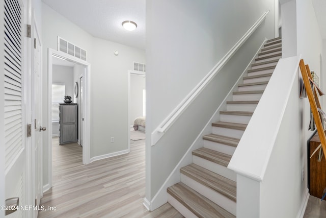 staircase featuring a textured ceiling and hardwood / wood-style floors