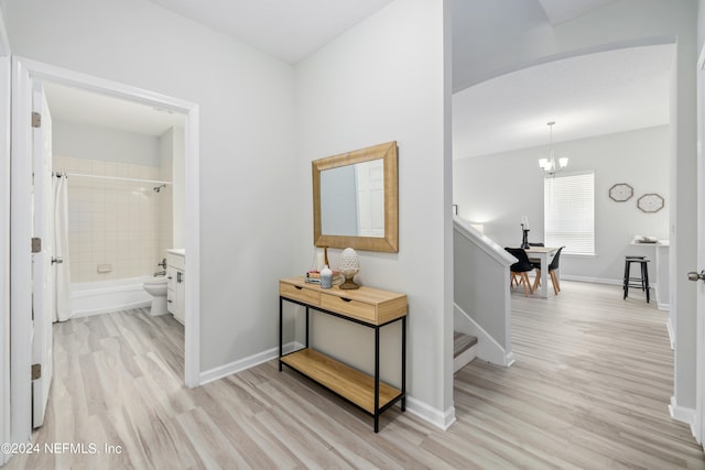 hallway featuring light hardwood / wood-style floors and an inviting chandelier