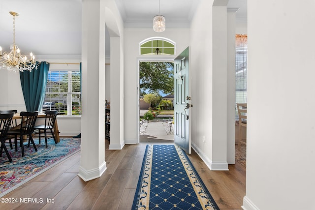 foyer with a notable chandelier, dark hardwood / wood-style floors, and crown molding