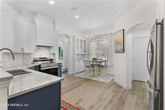 kitchen with white cabinets, hanging light fixtures, sink, light hardwood / wood-style flooring, and stainless steel appliances