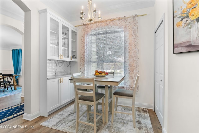 dining space featuring light wood-type flooring, crown molding, and a chandelier