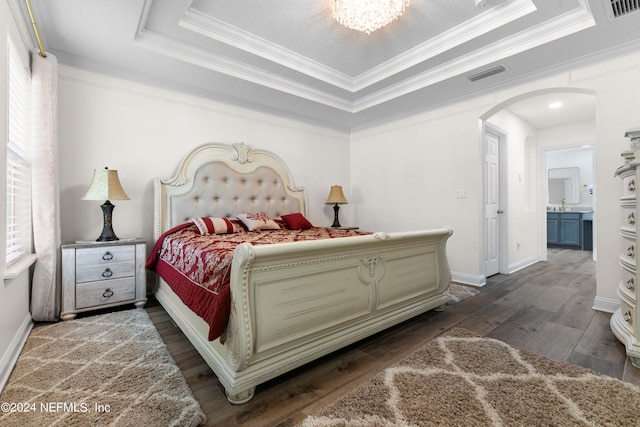 bedroom featuring a raised ceiling, dark hardwood / wood-style floors, and crown molding