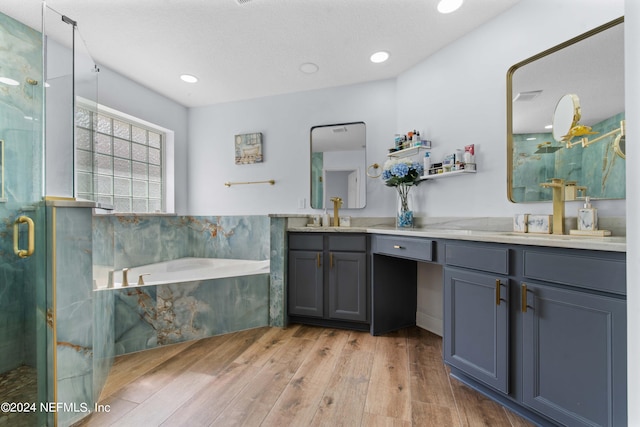 bathroom with a textured ceiling, independent shower and bath, vanity, and hardwood / wood-style flooring