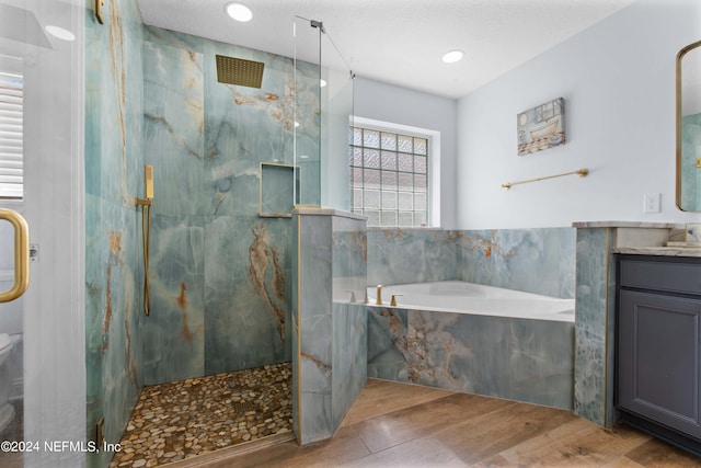 bathroom with independent shower and bath, vanity, hardwood / wood-style floors, and a textured ceiling