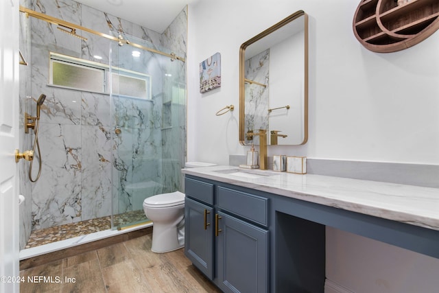 bathroom featuring wood-type flooring, vanity, toilet, and a shower with door