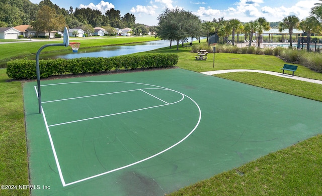 view of basketball court with a yard and a water view