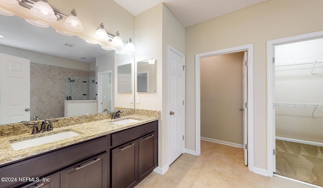 bathroom featuring vanity, tile patterned flooring, and a tile shower