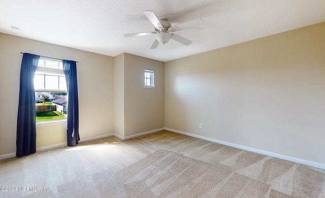 carpeted spare room featuring ceiling fan, a textured ceiling, and plenty of natural light