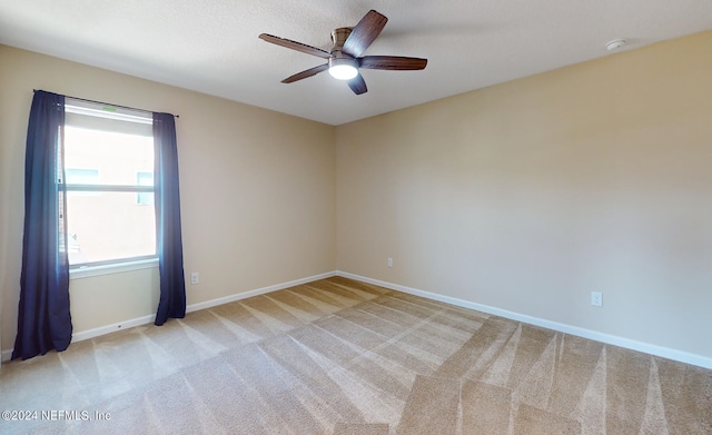 spare room with ceiling fan and light colored carpet