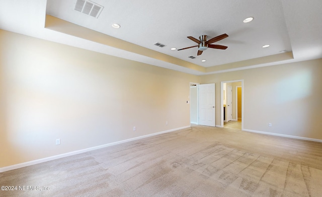 carpeted spare room with ceiling fan and a raised ceiling