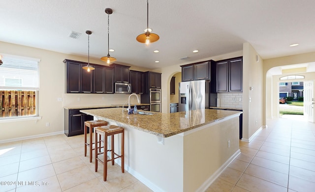 kitchen featuring appliances with stainless steel finishes, sink, an island with sink, and a breakfast bar