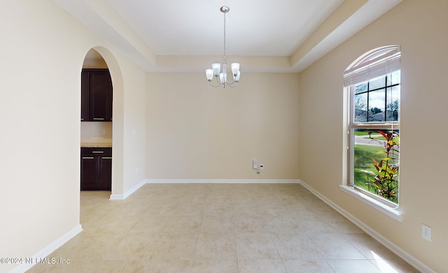 empty room with a notable chandelier and plenty of natural light