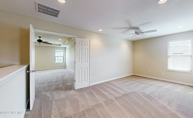 unfurnished room featuring light carpet, a textured ceiling, and ceiling fan