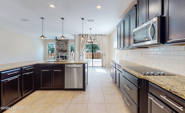 kitchen with pendant lighting, light tile patterned floors, sink, appliances with stainless steel finishes, and a fireplace