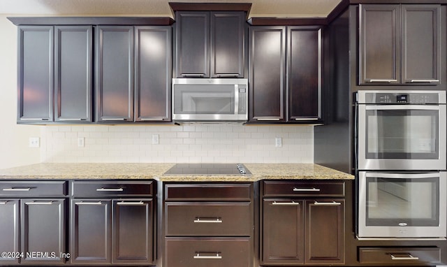 kitchen with dark brown cabinetry, light stone countertops, stainless steel appliances, and tasteful backsplash