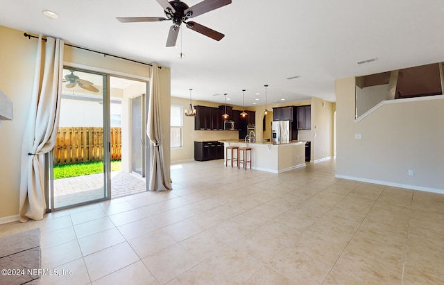 unfurnished living room with ceiling fan with notable chandelier and light tile patterned floors