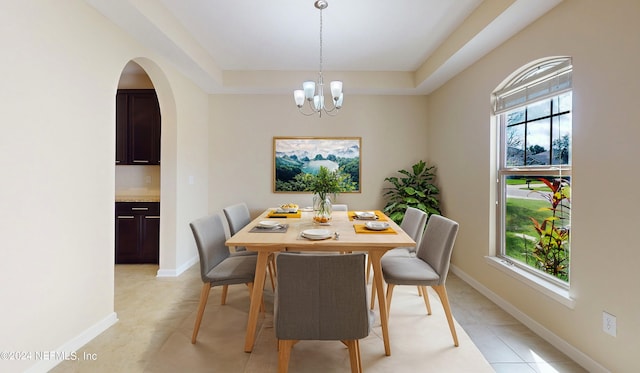 dining area featuring a raised ceiling, light tile patterned floors, and a chandelier