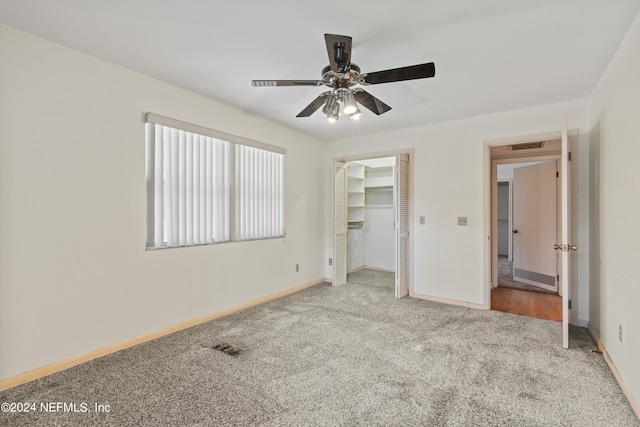 unfurnished bedroom featuring ceiling fan, light colored carpet, and a spacious closet