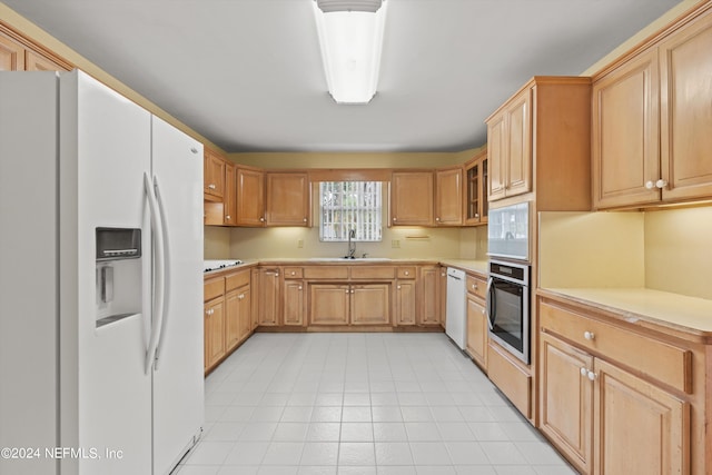 kitchen with light tile patterned floors, white appliances, sink, and light brown cabinets