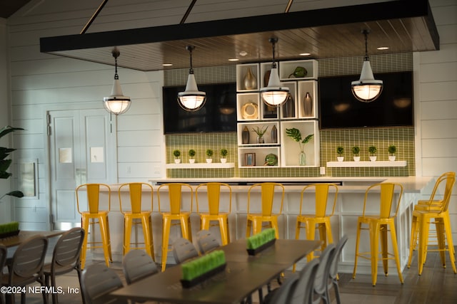 bar with tasteful backsplash, wood-type flooring, wood ceiling, hanging light fixtures, and beam ceiling