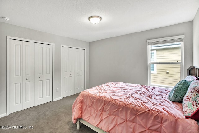 carpeted bedroom with a textured ceiling and multiple closets