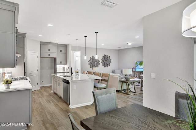 kitchen with gray cabinets, an island with sink, and dishwasher