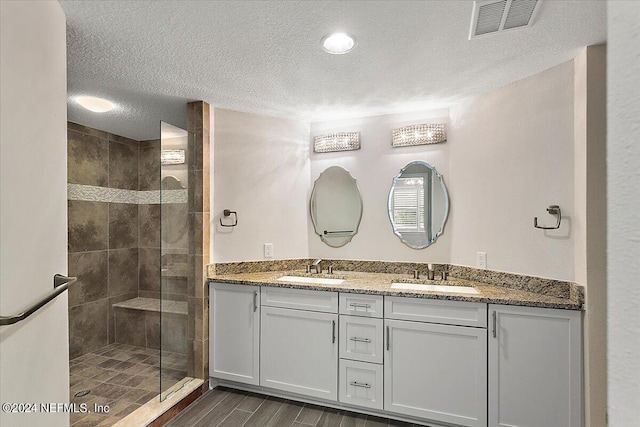 bathroom featuring tiled shower, a textured ceiling, and vanity