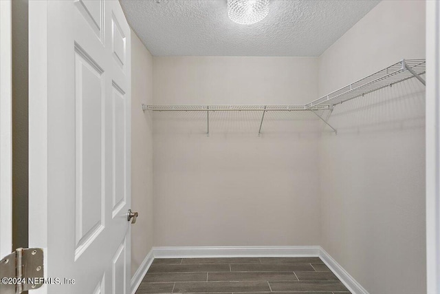 walk in closet with dark wood-type flooring