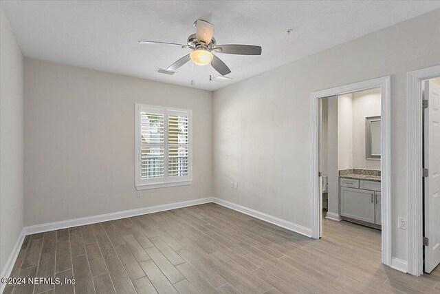 empty room featuring light hardwood / wood-style floors, ceiling fan, and a textured ceiling