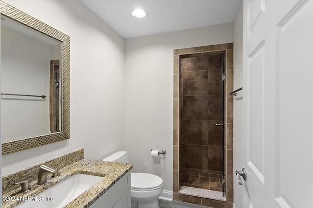 bathroom featuring toilet, vanity, and tiled shower